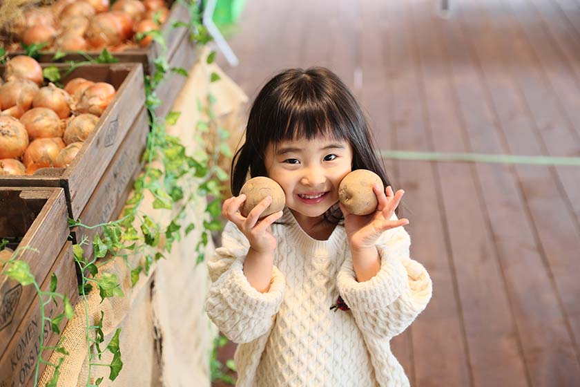 野菜マルシェでジャガイモを持つ女の子