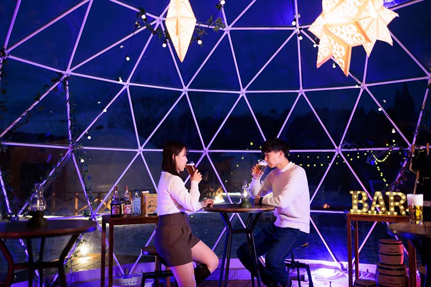 Two people enjoying drinks at the Free Bar at a glamping facility